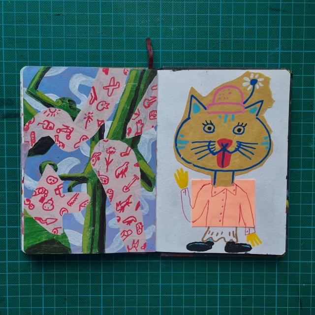 Artwork in an open sketchbook featuring abstract, colorful drawings of a cartoon cat and patterned abstract shapes on a green grid surface.