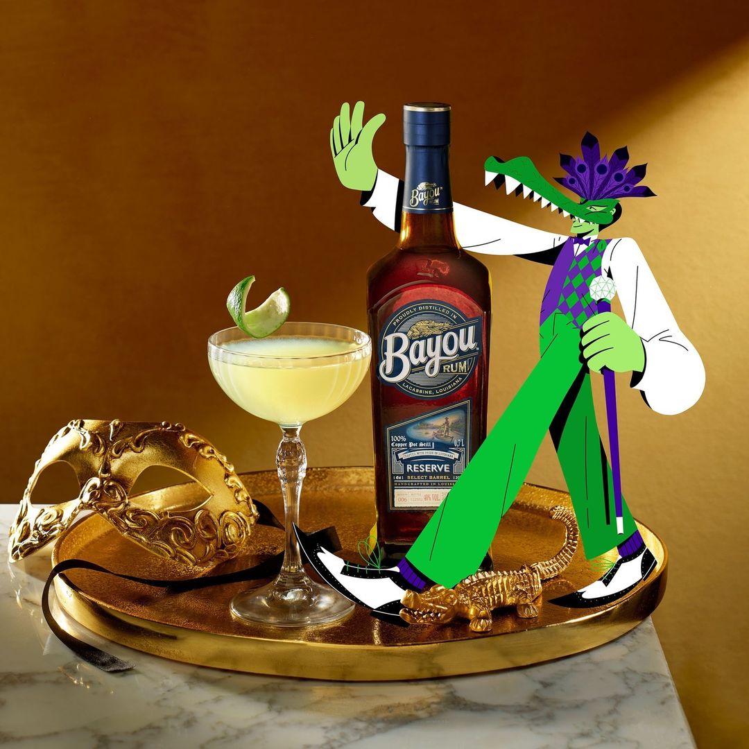 Still life of Bayou Rum bottle, cocktail, and Mardi Gras mask, with illustration of alligator in suit, on a gold tray.