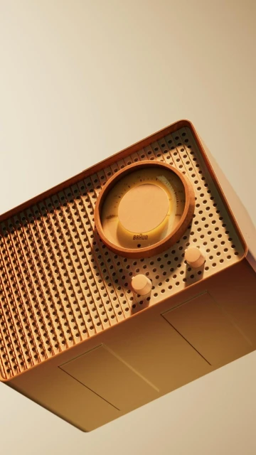 Angled view of a retro-style radio featuring a circular dial, speaker grill, and simple knobs against a light tan gradient background.