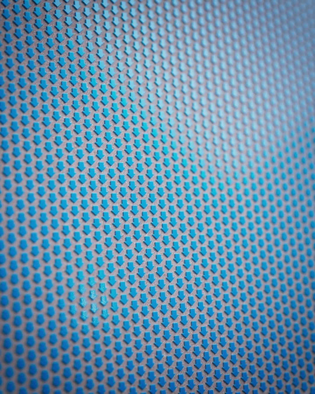 Close-up of a pattern featuring rows of downwards-pointing blue arrows on a gray background creating an abstract geometric texture.