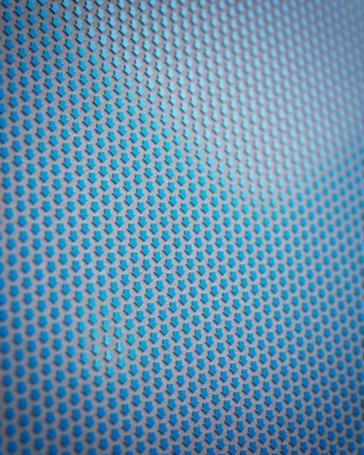 Close-up of a pattern featuring rows of downwards-pointing blue arrows on a gray background creating an abstract geometric texture.