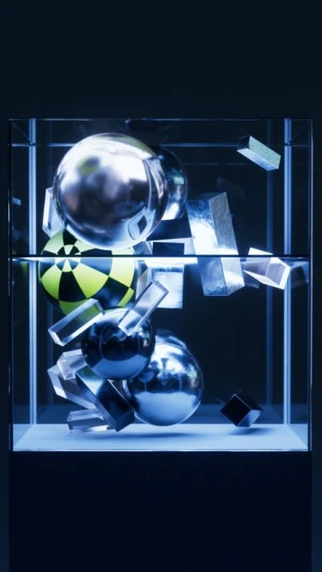 Geometric abstract: Spheres, cubes, and rectangular prisms float inside a clear display case against a dark, gradient blue background.