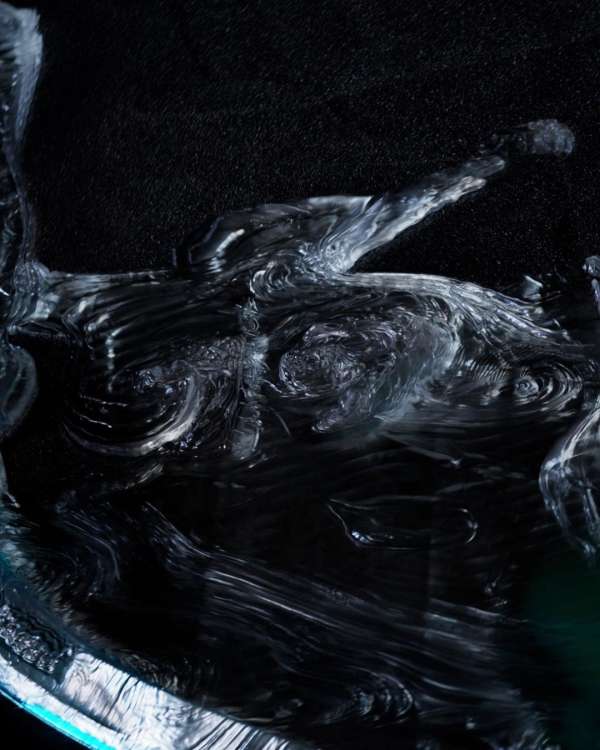 Abstract image features flowing, wave-like glass structures with dark background, creating an ethereal and dynamic visual effect.