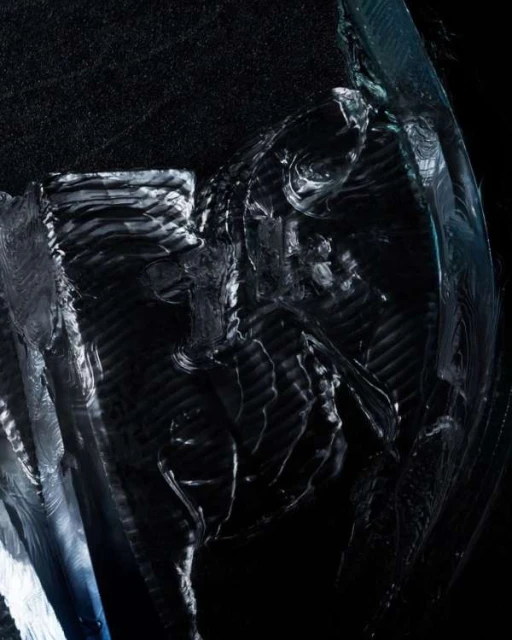 Abstract close-up shot of textured, reflective surface with dark, mottled background creating a mysterious, high-contrast visual.