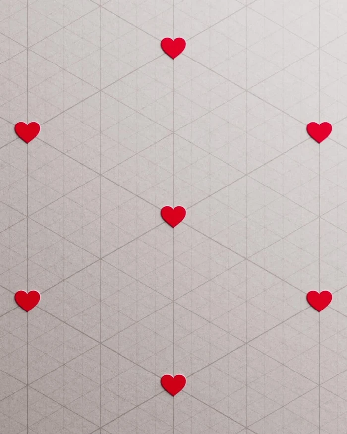 Several small red heart shapes arranged in a geometric pattern on a textured grey paper background with faint grid lines