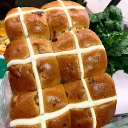 Close up of freshly baked golden brown hot cross buns with piped white crosses on top