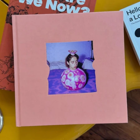 Pink square book with a central die-cut window displaying an image of a person inside a patterned pink sphere.