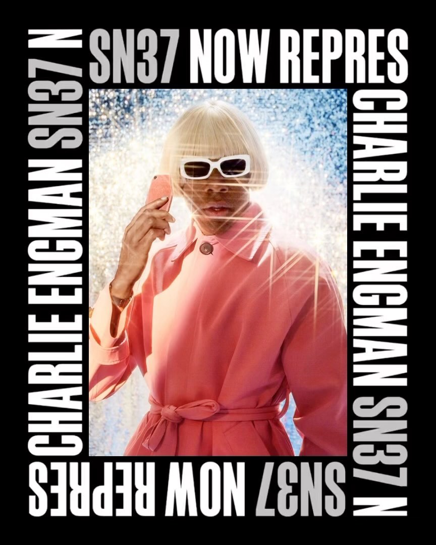 Person with blonde wig wearing sunglasses and a pink coat holding a phone, against a blue and white background with black text.