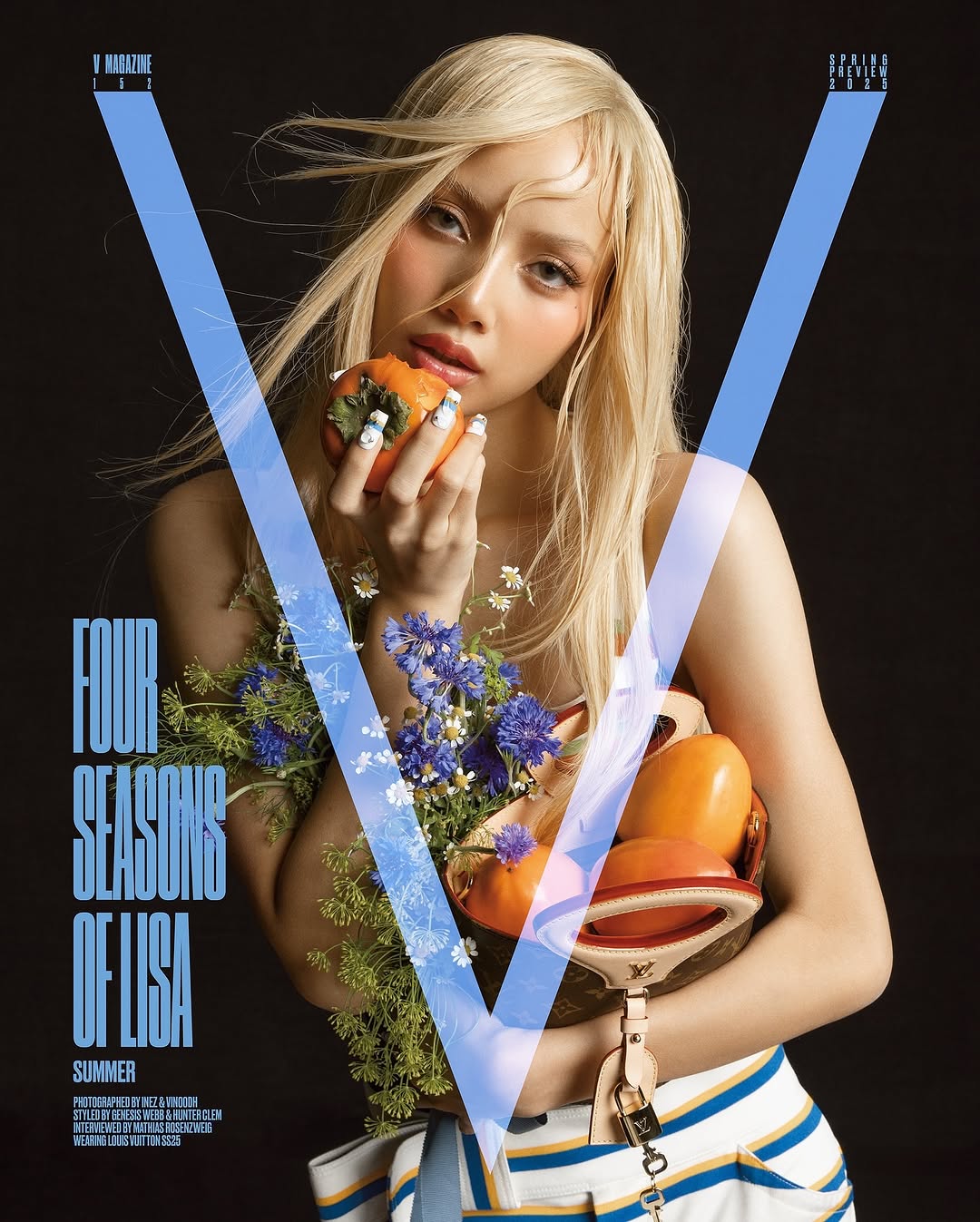 Magazine cover shot of a blond woman holding fruit and flowers, posing against a dark backdrop with a large blue 'V' graphic.