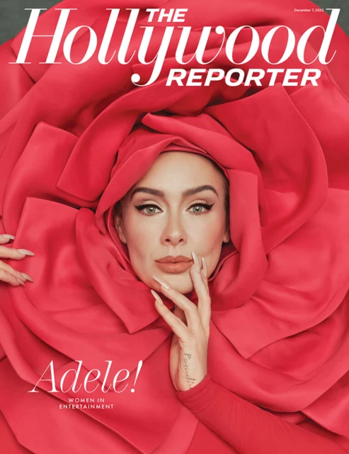 Adele poses on The Hollywood Reporter cover. Dressed in a large red rose-like garment, she rests a manicured hand near her face.