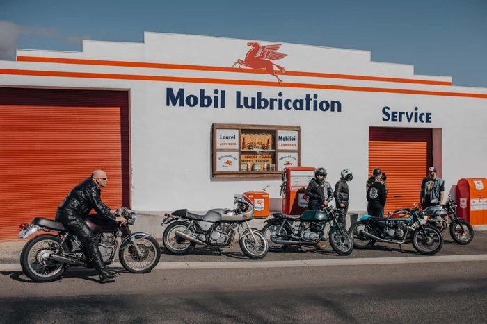 Group of motorcyclists and vintage motorcycles parked in front of a white building with Mobil Lubrication signage in Melbourne by Wren Steiner.