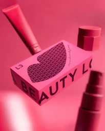 Pink cosmetic box and beauty products levitating against a pink background