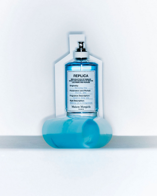 Blue glass fragrance bottle with label resting on a white surface and backdrop, designed by Natalie Turnbull