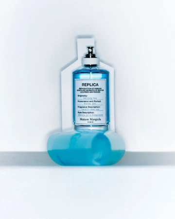 Blue glass fragrance bottle with label resting on a white surface and backdrop, designed by Natalie Turnbull