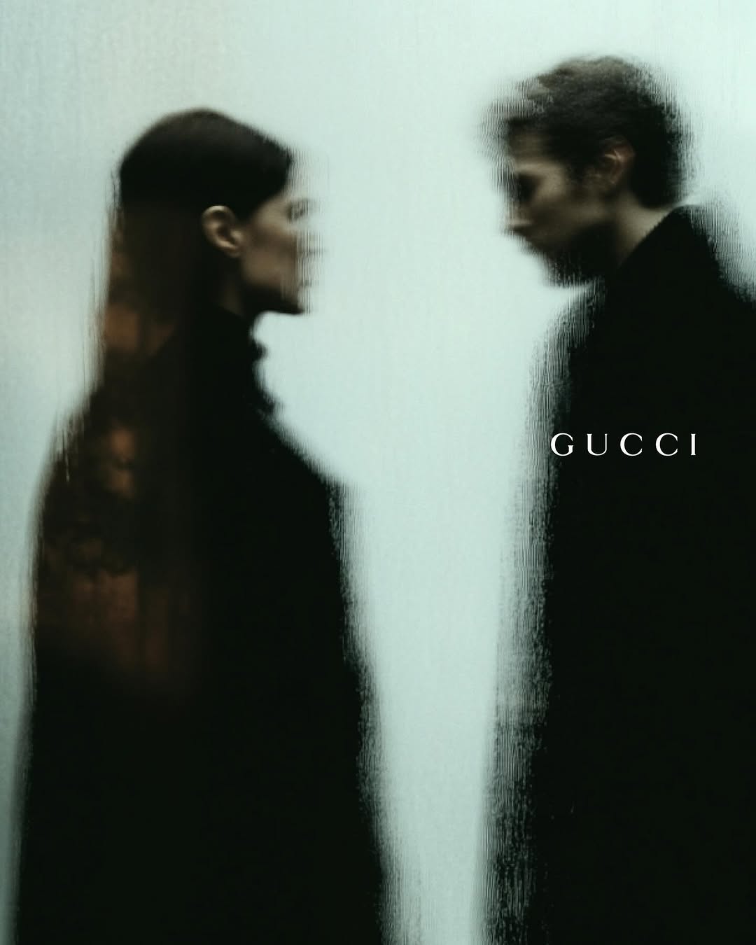 Fashion ad with an adult male and female couple posing, filtered through frosted glass. The brand name GUCCI is visible on the right side.