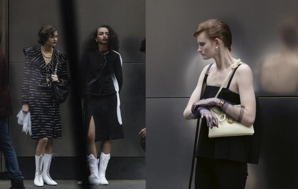 Three fashion models pose outdoors against a dark grey wall, wearing black-and-white vintage-style clothing, bags, and white boots.