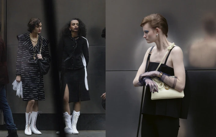Three fashion models pose outdoors against a dark grey wall, wearing black-and-white vintage-style clothing, bags, and white boots.