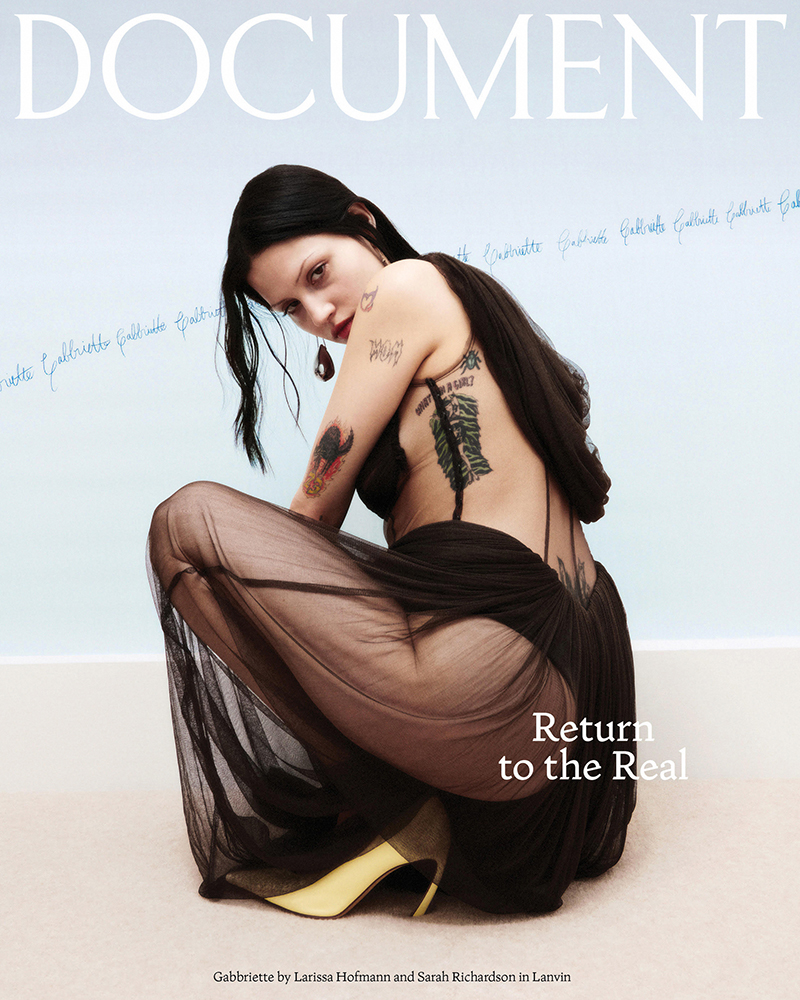 Magazine cover featuring a woman in a black dress and gold heels, crouching against a pale blue background with the word 'DOCUMENT' above.