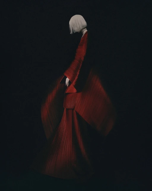 Woman in red pleated dress posing against a black background. The woman is facing away from the camera. The image has a dark and moody tone.