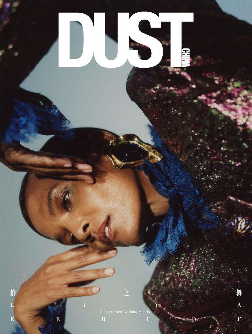 Magazine cover featuring a woman with golden jewelry, styled in a sequin jacket and blue ruffled collar, posing with her hands up.