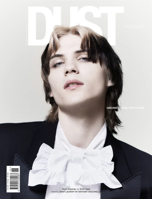 Dust magazine cover featuring a young adult with dyed hair wearing a suit jacket and white ruffled shirt, set against a light background.