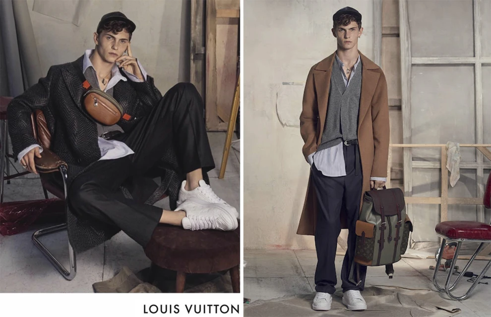 Two stylish adult males model Louis Vuitton apparel in a studio setting, showcasing designer coats, trousers, and accessories.