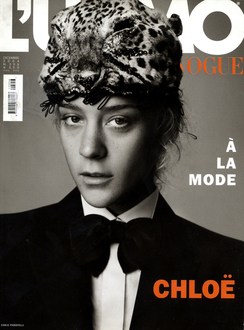Vogue magazine cover featuring a model wearing a leopard print hat, a black bow tie, and a blazer on a grey background with text overlays.