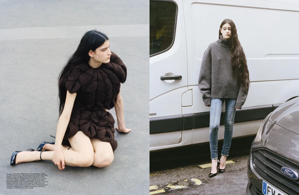Two women pose outdoors in fashionable clothing; one is wearing a brown textured garment, the other a gray sweater and jeans.