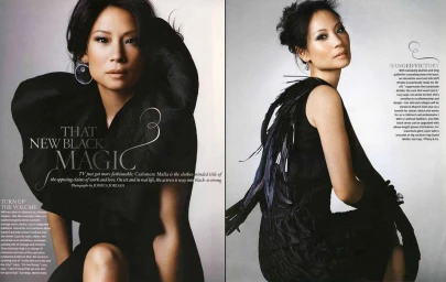 Lucy Liu wearing a black avant-garde dress with sculptural ruffles and feathers against a grey studio background.