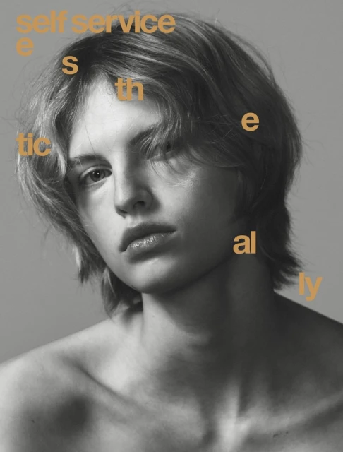 Portrait of a young adult with blond hair and bare shoulders, against a grey studio backdrop with graphic typography overlaid.