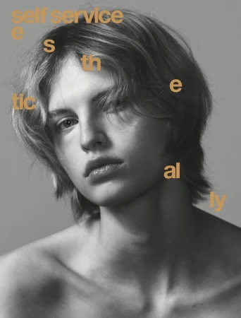 Portrait of a model with layered hair and neutral expression against a plain grey backdrop with yellow typography overlay