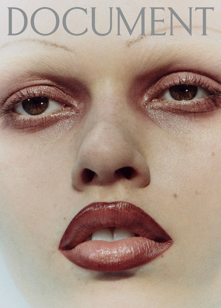 Close-up portrait of a woman's face with makeup, featuring glossy red lips and brown eyes, against a light background with the text 'DOCUMENT' above.