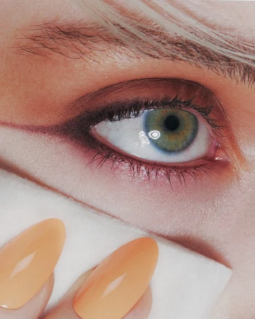 Close-up of a woman's eye with makeup, manicured fingernails, and a white cloth, showcasing beauty and cosmetic artistry.