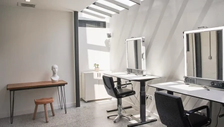 Bright photo studio interior in London with vanity mirrors, styling desks, and modern black chairs.