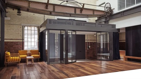 Interior of a London photo studio featuring exposed brick walls, wooden floors, and a modern glass meeting room pod.