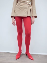 Model wearing a tan wrap jacket, vibrant red tights, and matching red pointed-toe heels against a plain white background.