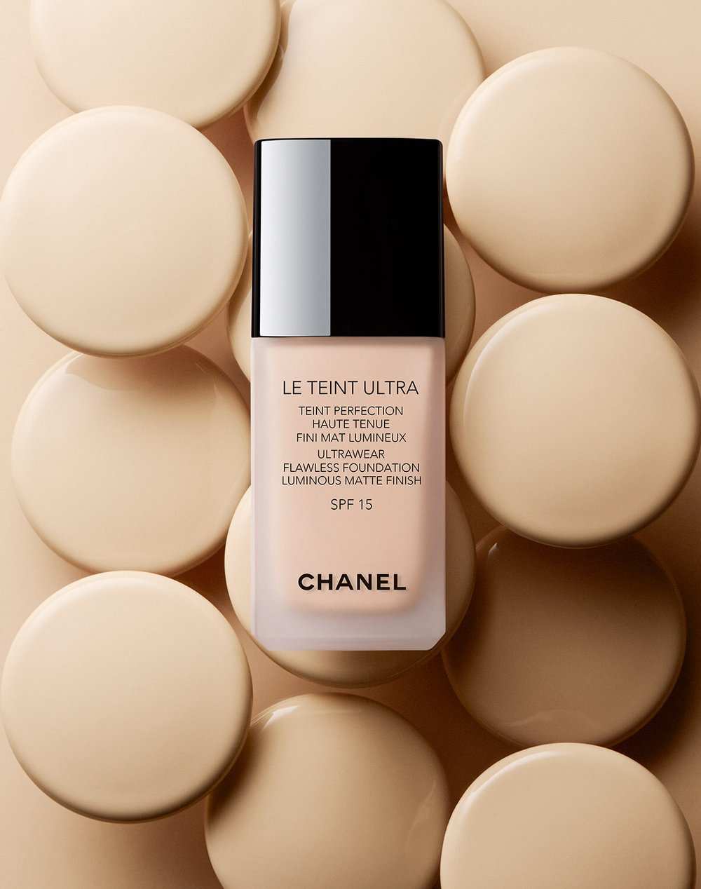 Chanel Le Teint Ultra foundation bottle on a beige background with circular discs, close-up product shot, beauty and cosmetics.