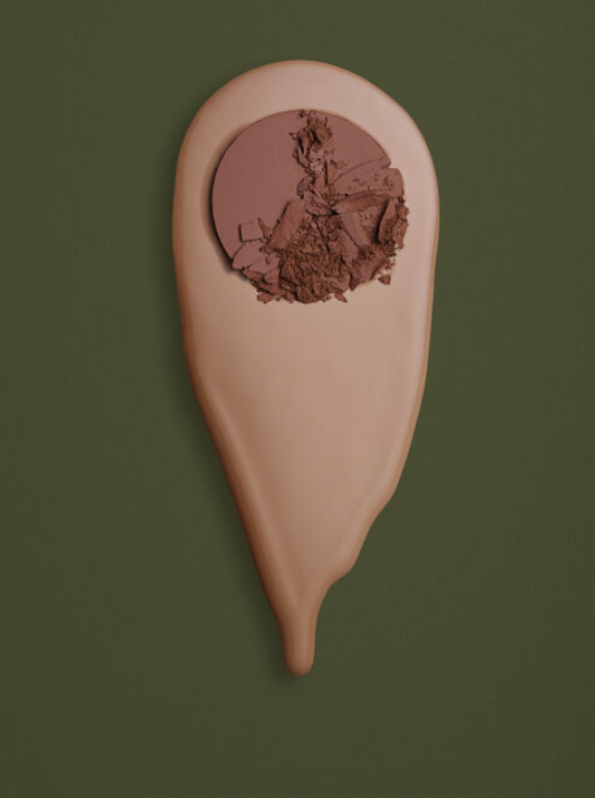 Tan foundation make up with cracked brown powder on a green background, beauty still life image. Cosmetics product.