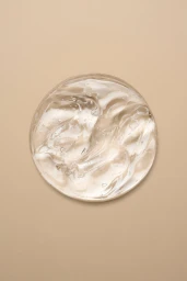 Circular dollop of clear transparent skincare gel with small air bubbles on a solid beige background