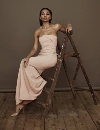 Woman in strapless pale pink gown sitting on a weathered wooden ladder inside a studio by photographer Lucia O'Connor-McCarthy.