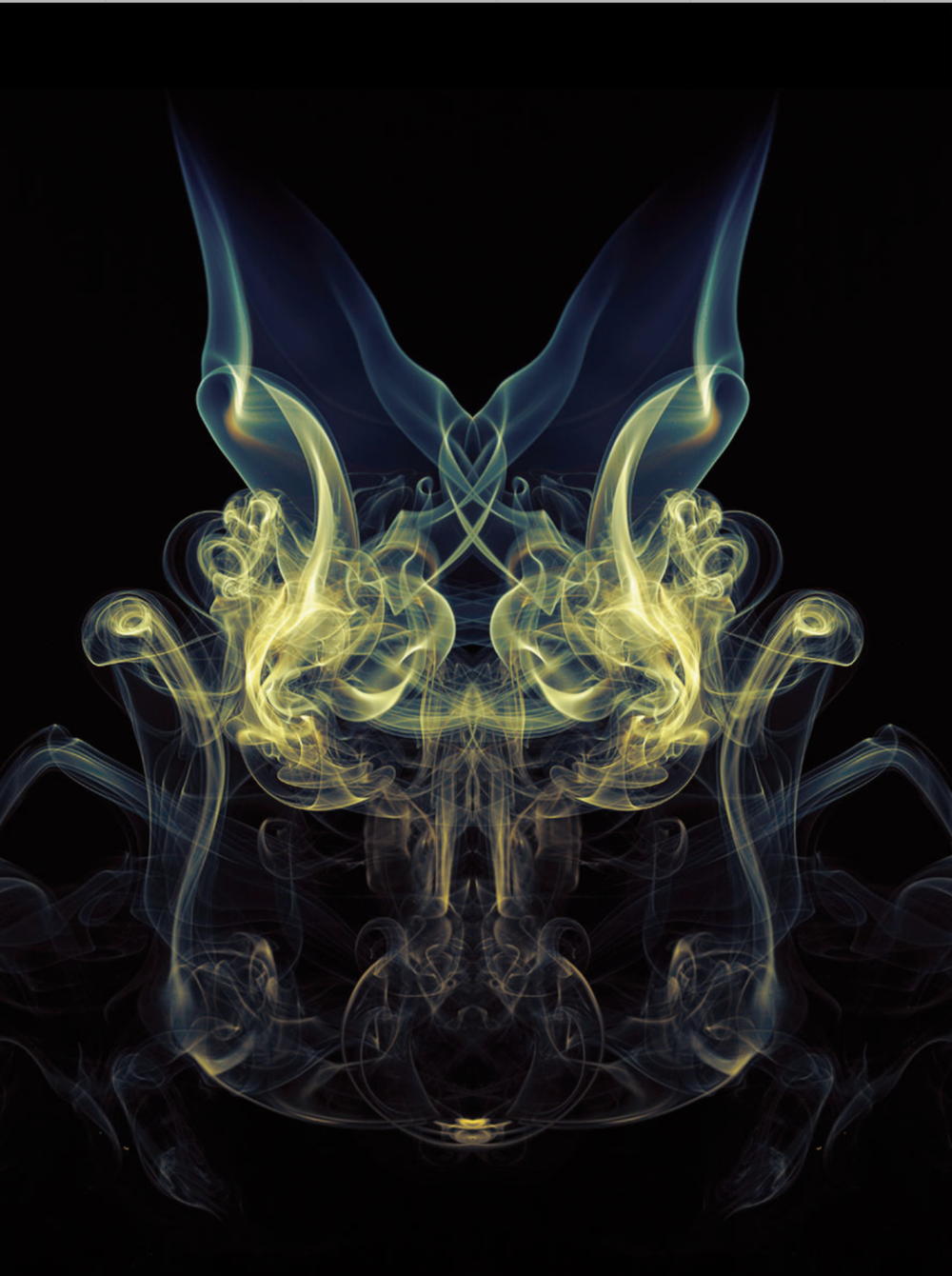 Abstract symmetrical smoke pattern against a black background, featuring delicate wisps of yellow, blue, and white smoke creating a ghostly figure.