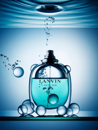 Lanvin Vetyver eau de toilette bottle in blue liquid with bubbles, against a light blue gradient background. Perfume still life.