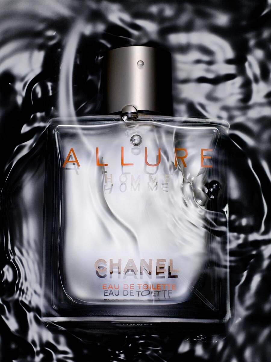 Close-up studio shot of a clear Chanel Allure Homme Eau de Toilette bottle with a silver cap, surrounded by water, and sleek dark background.