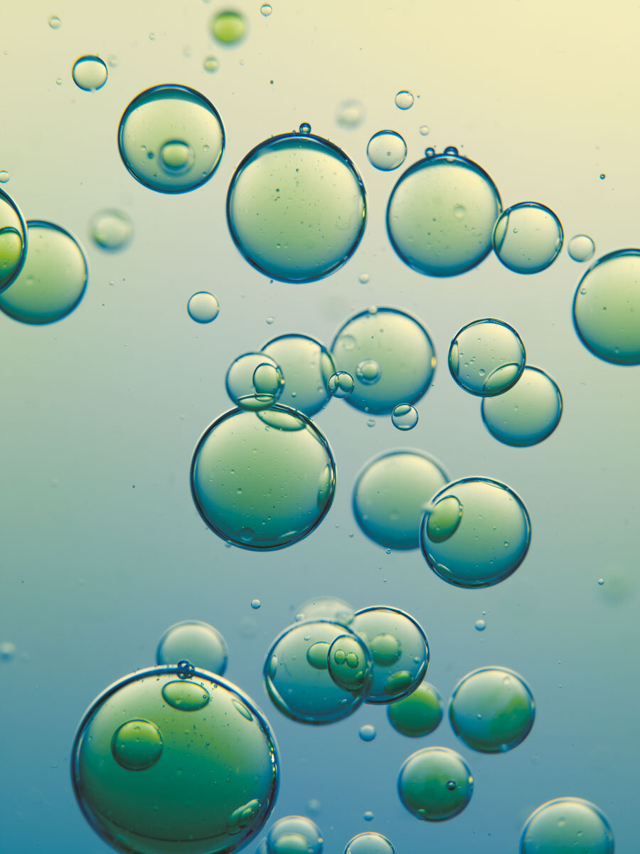 Abstract shot of translucent green and blue spheres of varying sizes against a soft gradient background, creating a serene and unique visual.