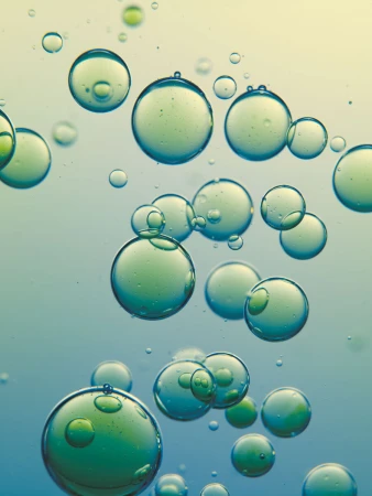 Abstract shot of translucent green and blue spheres of varying sizes against a soft gradient background, creating a serene and unique visual.