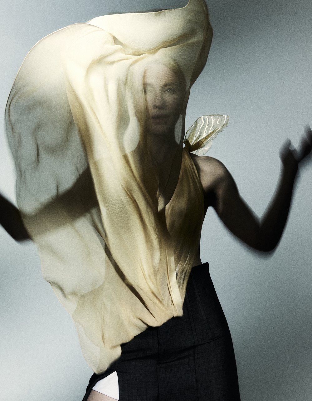 Woman in motion with flowing yellow fabric. Beauty shot in studio with movement, fashion, and a modern, ethereal feel and creative lighting.