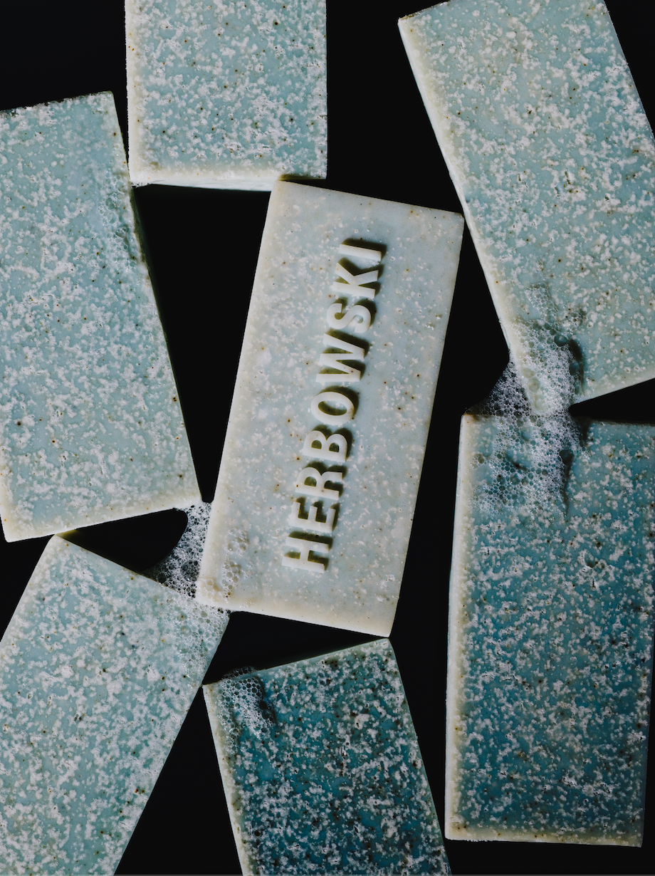 Several rectangular bars of light blue soap with a grainy texture and the name 'HERBOWSKI' embossed on one in the center.
