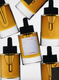 Multiple glass dropper bottles filled with golden amber oil arranged against a bright white background