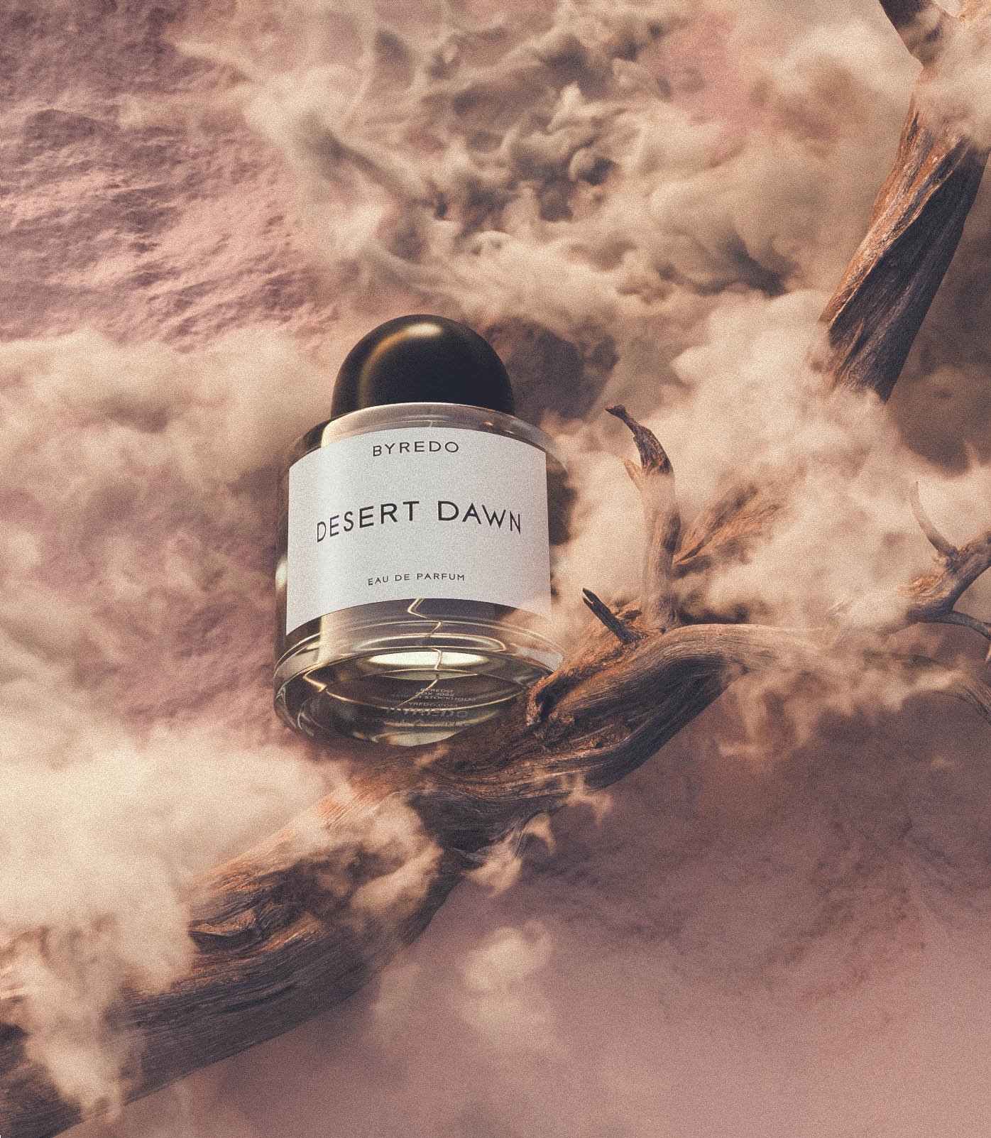 Byredo Desert Dawn perfume bottle presented on a fallen tree branch with smoky background, product shot for beauty and fragrance marketing.