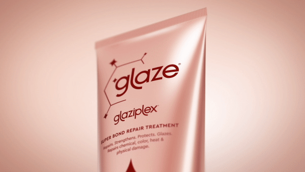 Close-up of a pink tube of Glaze hair repair treatment against a gradient background. Product promises to strengthen and protect hair.